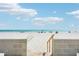 View of a sandy beach with beachgoers framed by a concrete walkway at 14300 Gulf Blvd # 401, Madeira Beach, FL 33708