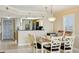 Dining area open to kitchen, featuring a pendant light and window with shutters at 14300 Gulf Blvd # 401, Madeira Beach, FL 33708