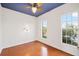 Cozy bedroom boasts two bright windows, ceiling fan, unique flooring, and a painted accent ceiling at 14648 Bournemouth Rd, Tampa, FL 33626