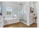 Bright bathroom featuring a soaking tub, glass-enclosed shower with subway tile, and wood-look flooring at 14910 Tom Fazio Ct, Tampa, FL 33626