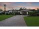 Exterior view of a house with well-manicured lawn, mature landscaping, and a brick-paved driveway at 14910 Tom Fazio Ct, Tampa, FL 33626