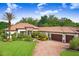Beautiful single-story home featuring a clay tile roof, lush landscaping, and a brick paved driveway at 14910 Tom Fazio Ct, Tampa, FL 33626