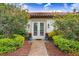 Inviting front entry with white doors, flanking foliage and planters with accent wall mounted lighting at 14910 Tom Fazio Ct, Tampa, FL 33626