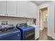 Functional laundry area with blue washer and dryer, built-in cabinets, and a utility sink at 14910 Tom Fazio Ct, Tampa, FL 33626