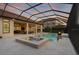 Stunning screened-in pool area with a spa, lounge chairs, umbrellas, fire bowls, and an outdoor kitchen at 14910 Tom Fazio Ct, Tampa, FL 33626