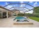 Luxurious screened-in pool with a spa, lounge chairs, an umbrella, fire bowls and lush landscaping at 14910 Tom Fazio Ct, Tampa, FL 33626