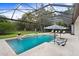 Relaxing screened-in pool area with comfortable lounge chairs, an umbrella, and tranquil landscaping at 14910 Tom Fazio Ct, Tampa, FL 33626