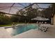 Beautiful screened-in pool with spa, lounge chairs, umbrellas, and fire bowls surrounded by lush landscaping at 14910 Tom Fazio Ct, Tampa, FL 33626