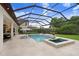 Inviting screened-in pool with a spa, lounge chairs, an umbrella, fire bowls and green backyard at 14910 Tom Fazio Ct, Tampa, FL 33626