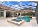 Resort-style screened-in pool with a spa, in-pool lounge chairs, umbrellas, fire bowls, and an outdoor kitchen at 14910 Tom Fazio Ct, Tampa, FL 33626