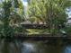 Backyard and waterfront view featuring mature trees and waterside access at 18712 Lakeshore Dr, Lutz, FL 33549