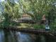 Spacious backyard with a waterfront view, mature trees, and a covered patio area at 18712 Lakeshore Dr, Lutz, FL 33549