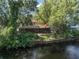 View of the backyard from the water showcasing the screened-in porch and mature trees at 18712 Lakeshore Dr, Lutz, FL 33549