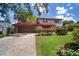 Two-story house with red roof, manicured landscaping, and brick driveway at 18712 Lakeshore Dr, Lutz, FL 33549