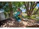 Backyard view of a charming wooden playset, surrounded by lush greenery and mature trees at 18712 Lakeshore Dr, Lutz, FL 33549