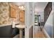 Cozy half-bathroom featuring a pedestal sink, decorative wallpaper, and adjacent hallway access at 18712 Lakeshore Dr, Lutz, FL 33549