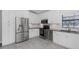 A bright white kitchen includes stainless steel appliances, white cabinets, granite countertops, and tiled flooring at 200 Pinewinds Blvd, Oldsmar, FL 34677