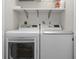 Bright laundry area with white washer and dryer and storage shelf above at 200 Pinewinds Blvd, Oldsmar, FL 34677