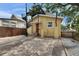 Quaint yellow house featuring a spiral staircase, brick pavers, a fenced yard, and mature trees at 2402 Harper St, Tampa, FL 33605