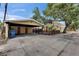 Exterior shot of a carport offering sheltered parking, highlighted by lush trees and a blue sky at 2402 Harper St, Tampa, FL 33605