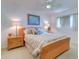 Bright bedroom with a ceiling fan, lamps and nightstands on either side of the wooden bedframe at 2504 Gulf Blvd # 201, Indian Rocks Beach, FL 33785