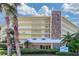 Exterior view of the Dolphin Reef condo building with stone accents, manicured landscaping, and palm trees at 2504 Gulf Blvd # 201, Indian Rocks Beach, FL 33785