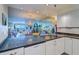 A kitchen with granite counters, white cabinetry, a mirrored backsplash, and a view to the living room at 2504 Gulf Blvd # 201, Indian Rocks Beach, FL 33785