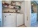 Bright laundry room with white washer and dryer, storage shelves, and arched doorway at 2504 Gulf Blvd # 201, Indian Rocks Beach, FL 33785