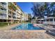 A beautiful outdoor pool area with a hot tub and a grilling station with a building in the background at 2504 Gulf Blvd # 201, Indian Rocks Beach, FL 33785