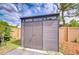 Modern shed featuring a sleek design, complemented by lush landscaping and a view of the backyard at 2524 Laurelwood Ln, Valrico, FL 33596