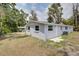 Exterior view of a home's backyard with dry grass, a fence, and lush trees at 2608 Browning St, Sarasota, FL 34237