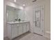 Bright bathroom featuring double sinks, white cabinets, a large mirror, and a shower with a glass door at 2858 Star Anise Ln, Wimauma, FL 33598