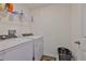 Bright laundry room with white appliances, overhead shelving for storage, and tiled flooring at 2858 Star Anise Ln, Wimauma, FL 33598