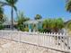 Charming light blue home with white trim, manicured front yard, tropical landscaping, and a white picket fence at 3031 56Th S St, Gulfport, FL 33707