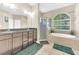 Bright bathroom features double vanity, soaking tub under window, and glass enclosed shower at 311 Parsons Woods Dr, Seffner, FL 33584