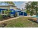A view of the backyard featuring grass, a walkway, landscaping, and the side of the blue and white home at 330 Pineapple St, Tarpon Springs, FL 34689