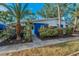 A charming blue home with tropical landscaping, showcasing its curb appeal and serene setting at 330 Pineapple St, Tarpon Springs, FL 34689