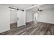Bright main bedroom featuring modern sliding barn door, grey wood flooring, and open closet at 330 Pineapple St, Tarpon Springs, FL 34689