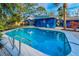 Inviting backyard pool with clear blue water, ladder, patio and chairs, surrounded by mature trees at 330 Pineapple St, Tarpon Springs, FL 34689