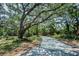 Crushed-shell driveway winding through mature trees and lush landscaping at 420 Hanby St, Crystal Beach, FL 34681