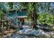 Backyard showcasing a charming home with a screened porch and outdoor seating amidst mature trees and lush landscaping at 420 Hanby St, Crystal Beach, FL 34681