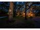 Home illuminated at dusk, surrounded by mature trees and lush landscaping at 420 Hanby St, Crystal Beach, FL 34681