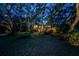 Home illuminated at dusk, surrounded by mature trees and lush landscaping at 420 Hanby St, Crystal Beach, FL 34681