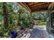 Charming outdoor patio with brick flooring, vibrant green plants, and a serene view of the surrounding greenery at 420 Hanby St, Crystal Beach, FL 34681
