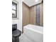 Contemporary bathroom featuring a soaking tub with black hardware and unique wood-style tiling with stone accents at 430 Hickory Nut, Oldsmar, FL 34677