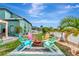 Backyard features a cozy fire pit surrounded by colorful Adirondack chairs, tropical landscaping, and white picket fence at 5103 Rushbrook Rd, Land O Lakes, FL 34638