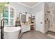 Bright bathroom features a soaking tub under a decorative window and a shower with gray tile at 5103 Rushbrook Rd, Land O Lakes, FL 34638