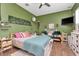 Green bedroom featuring a bed, couch, mounted television, hardwood floors, and a ceiling fan at 5103 Rushbrook Rd, Land O Lakes, FL 34638