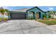 Beautiful teal home featuring manicured landscaping, red front door, and a two-car garage at 5103 Rushbrook Rd, Land O Lakes, FL 34638
