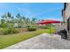 Spacious backyard featuring a patio area with a red umbrella and lush greenery at 5103 San Martino Dr, Wesley Chapel, FL 33543